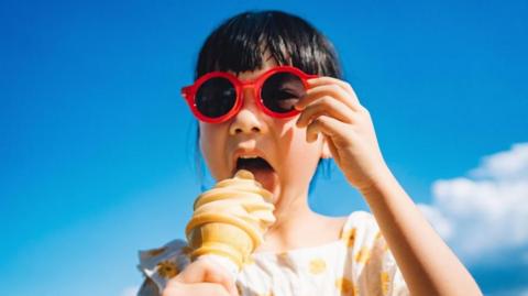 A girl in sunglasses eating an ice cream