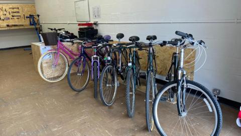 A row of 7 bikes some suitable for children 