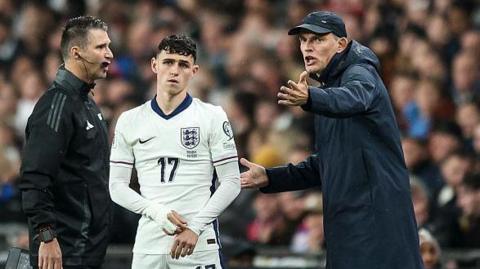 Thomas Tuchel gesticulates while standing next to Phil Foden