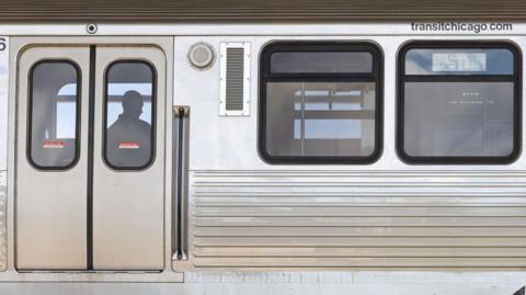 A police investigator works inside a CTA Blue Line train parked at the suburban Forest Park station