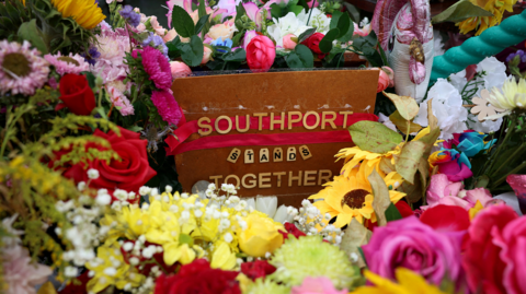 Flowers left in memory of the victims of the Southport attacks of 29 July 2024. Among the flowers is a placard that says 'Southport stands together'