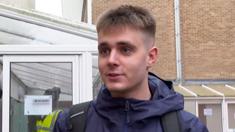 A young man with short hair wearing a blue jacket