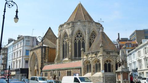 Street scene showing a church, parked cars, street lamp and buildings