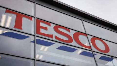 A store sign on the outside of a Tesco branch.