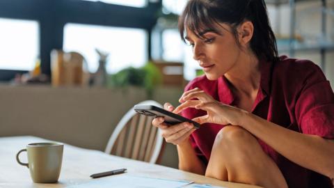 Person looking at bills and operating a smart phone