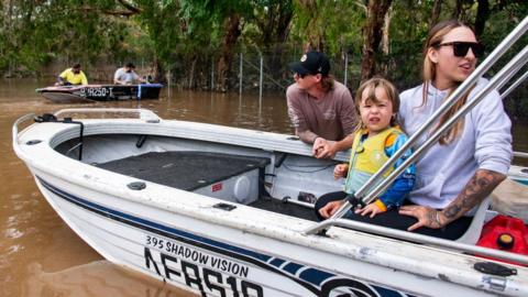 People in a boat in floodwaters in northern Queensland