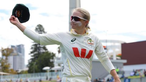 Australia captain Alyssa Healy raises her cap in the air as she walks off the field