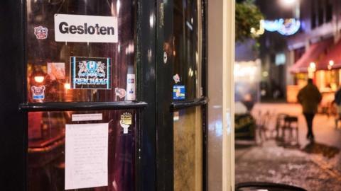 A sign that reads "Closed" in Dutch at a cafe door in the Dutch city The Hague. Photo: November 2021