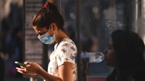 Woman in face mask looking at mobile phone