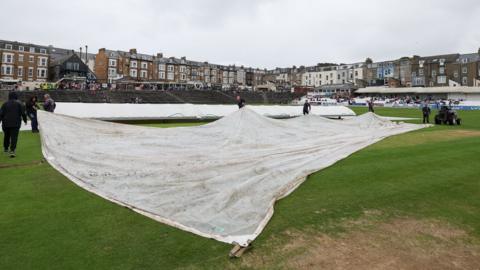 Groundstaff pull on the covers at North Marine Road