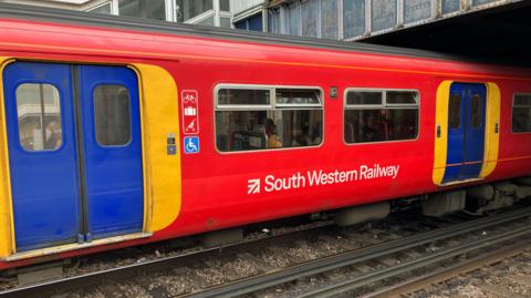 Red South Western Railway carriage at Clapham Junction station with blue and yellow doors