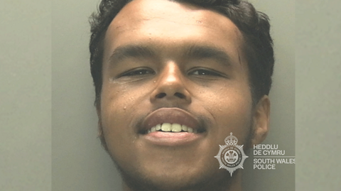 Custody photo of Rasheed Jama smiling towards the camera