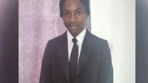 Ashraf Habimana: A boy with black hair, wearing a black jacket, white shirt and black tie. 


