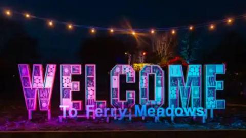 A sign that reads "Welcome to Ferry Meadows" is lit up in pink and blue. 