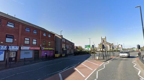 A generic view of Yorkshire Street. A church is in the background and shops to the side of the road.