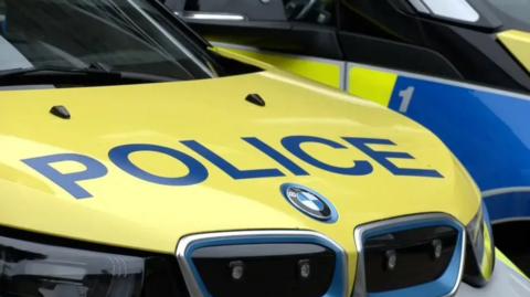 The yellow bonnet of a police car with POLICE in navy over the bonnet, BMW