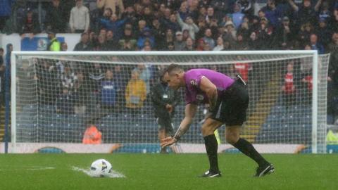 Referee Steve Martin tests a ball on a sodden pitch at Ewood Park on Saturday