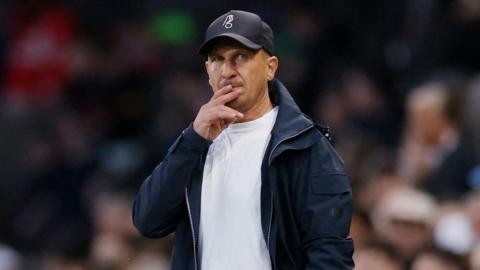 Gerhard Struber holding two fingers near his mouth while standing on the touchline