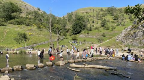 Groups of people crossing a river using stepping stones