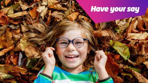 child lying down in autumn leaves