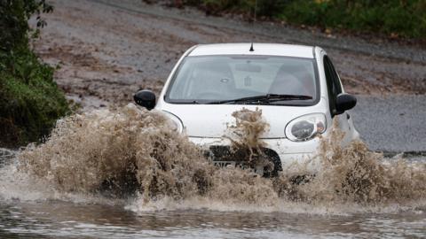 A car drives along a flooded road