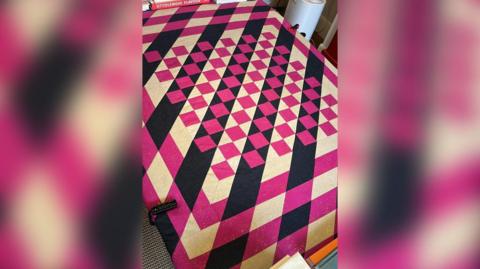 The quilt is pink and dark blue in a chequered pattern