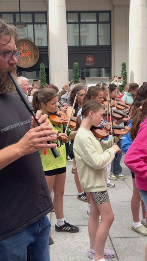 Young musicians playing violins in St Anne's Square.