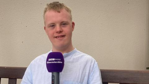 Jack holding a BBC Radio Gloucestershire microphone and smiling