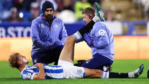 Huddersfield defender Michal Helik receives treatment after injuring his hamstring against Blackpool.