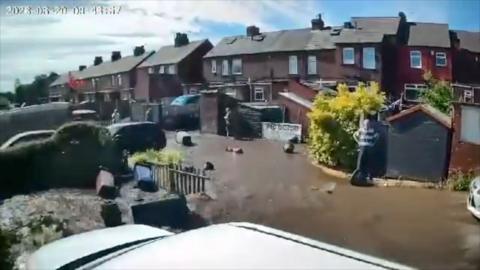 CCTV footage of a number of gardens and parking spaces flooded with brown water.