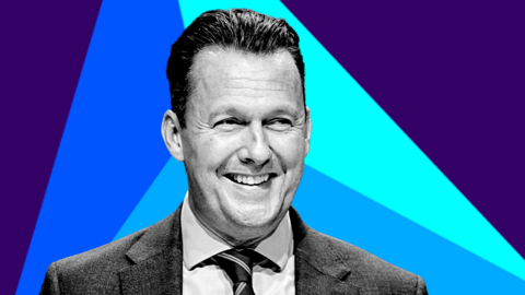 Russell Findlay is wearing a shirt and tie. He is pictured in black and white, against a colourful background. 