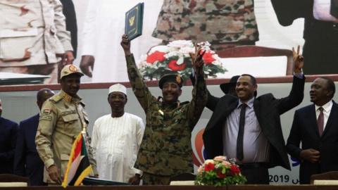 Protest leader Ahmed al-Rabie (2nd-R) alongside Lt-Gen Abdel Fattah Abdelrahman Burhan (C), head of Sudan's ruling Transitional Military Council during the signing ceremony in Khartoum on August 17, 2019, accompanied by General Hamdan Daglo "Hemeti" (2nd-L), TMC deputy chief and commander of the Rapid Support Forces paramilitaries, Ethiopian Prime Minister Abiy Ahmed (L), and Chadian President Idriss Deby (3rd-L)