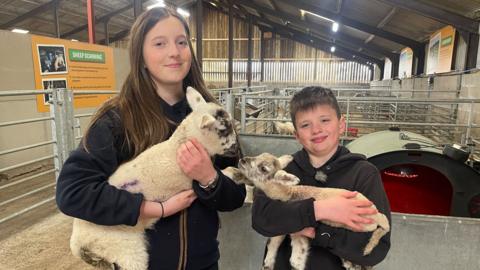 Maddie and Max holding a lamb each 