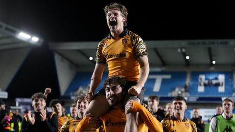 Hull City's Regan Slater, wearing the amber and black kit, is carried on the shoulders of a team-mate at the final whistle after the Championship play-off semi-final second leg match at The Den in London
