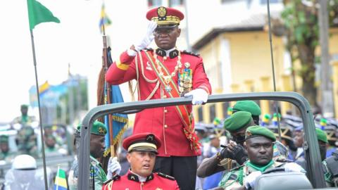 In an open top car, the leader of Gabon's military junta General Brice Oligui Nguema reviews his troops after being sworn in as interim president.