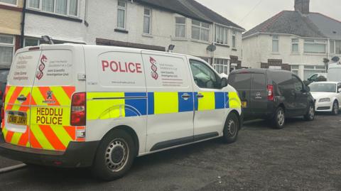 A white terraced house with a police van outside