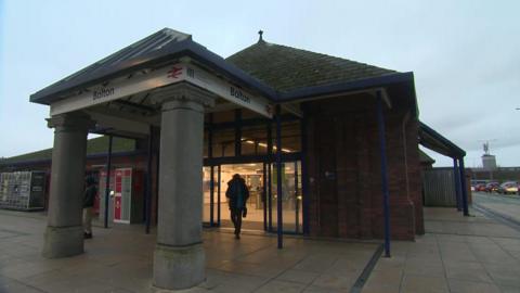 A man walks out of the entrance to Bolton railway station.