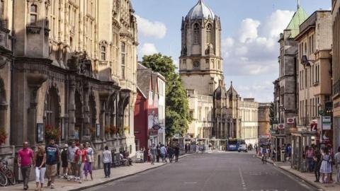 A picture of St Aldates in Oxford. On the left is the town hall, whilst a large tower if further down.