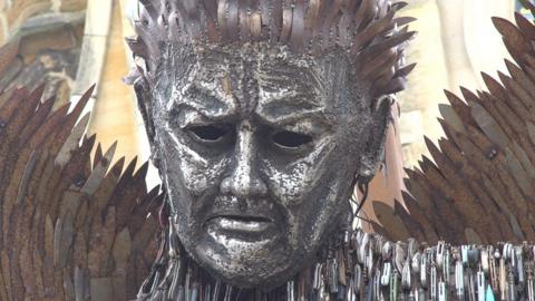 The knife angel. A 27ft-tall (8m) sculpture in the shape of an angel pulling a sad face, made from 100,000 blades.