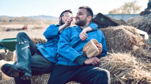 Two men hugging on hay