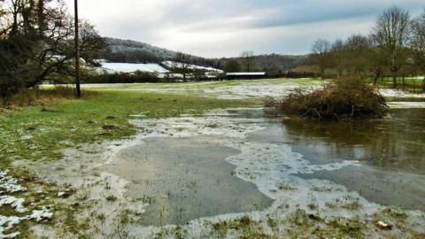 Ice on floodwater over a field in Shropshire. Snow is on the hills in the background. Picture by Peter Steggles