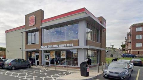 Burger King in Ryhope Road. It is a two-storey beige and brown building with large windows and the logo of the chain. There is a writing Flame Grilling Since 1954 above the entrance.