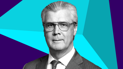 Malcolm Offord, who has grey hair swept back and glasses, in a down the lens shot. He is wearing a business suit, with a blue digitised graphic behind him. 