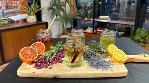 An array of Anna's honey's on a board with some sliced blood oragne, lemon, and some dried rose petals and lavender 