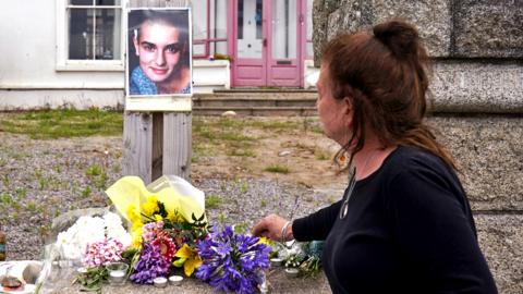 A person lays flowers outside the late Sinead O'Connor's former home in Bray, Co Wicklow on 27 July 2023