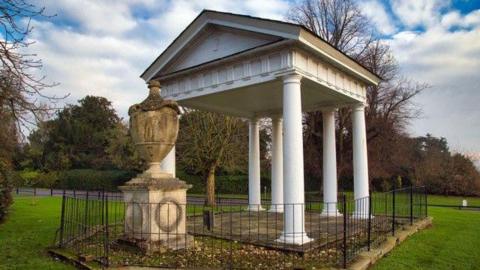 A white temple-like structure with a large urn beside it.