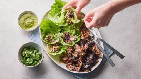 Lamb ssam on a white plate on a pale grey background.