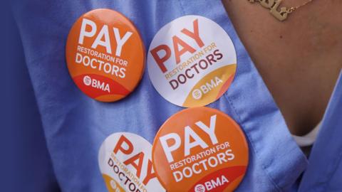 'Pay restoration for doctors' stickers and badge on scrubs