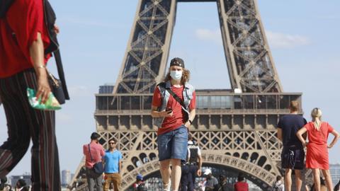 Tourist in front of Eiffel Tower with mask on