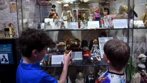 Two children looking at a variety of toys from different eras displayed at museum in Kent.